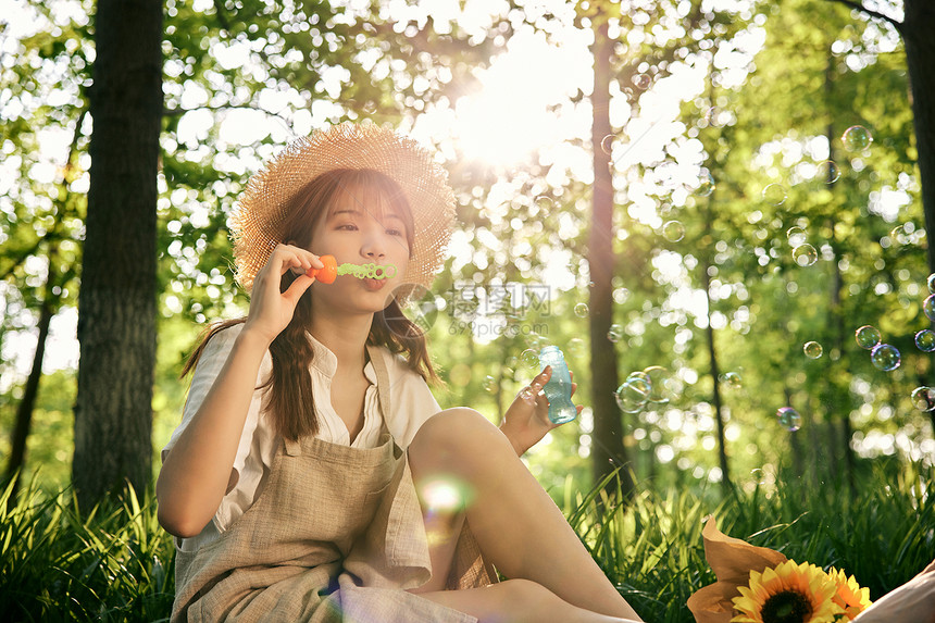 坐在草地前吹泡泡的清新夏日美女图片