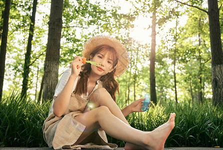 坐在草地前吹泡泡的清新夏日美女图片