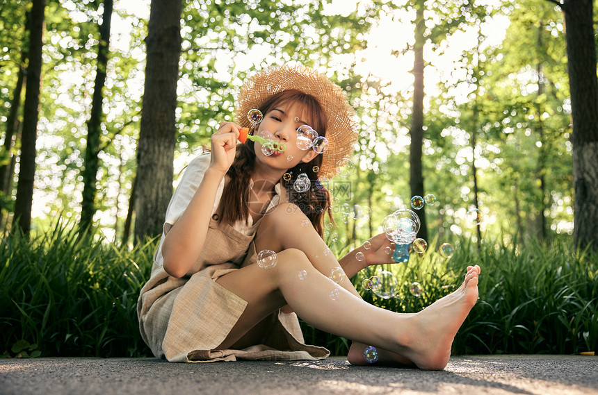 坐在草地前吹泡泡的清新夏日美女图片