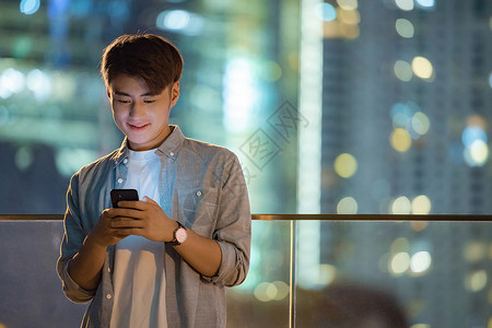 机会不等人夜晚城市里看手机的男青年背景