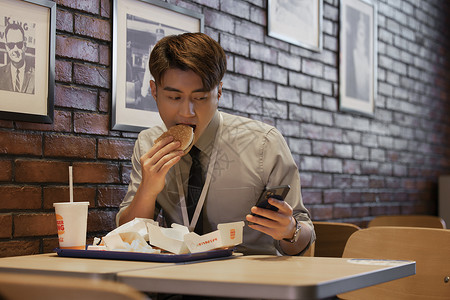 亚洲快餐职场男性吃饭时看手机背景