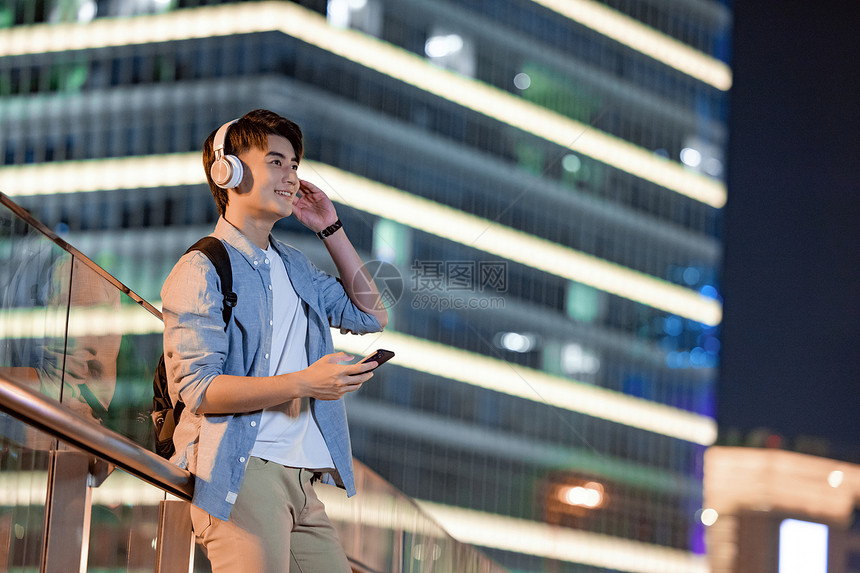 夜晚城市里戴着耳机的男性青年图片