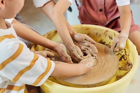 暑期美术陶艺老师辅助小朋友制作陶艺品背景
