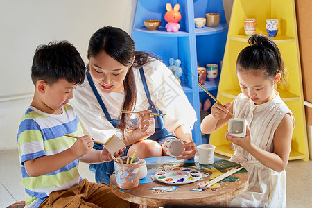 艺术老师教小朋友陶罐作画背景图片