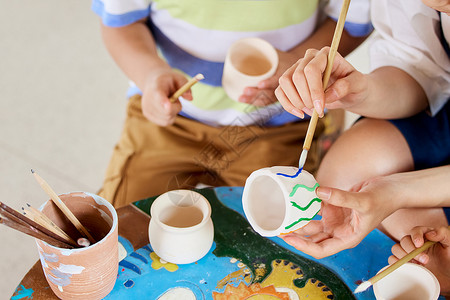 少儿美术教育老师教小朋友陶罐作画特写背景
