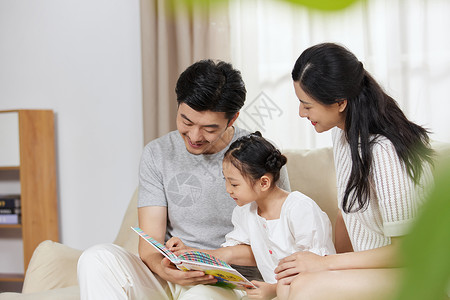 一家人读书一家三口在沙发上看故事书背景
