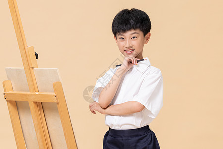 站在画板前绘画的小男孩背景图片