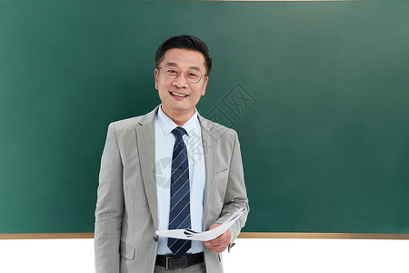 中年教授手拿讲义站在黑板前图片