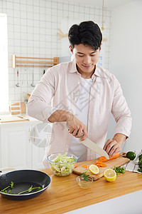 帅气的年轻男士在厨房切菜图片