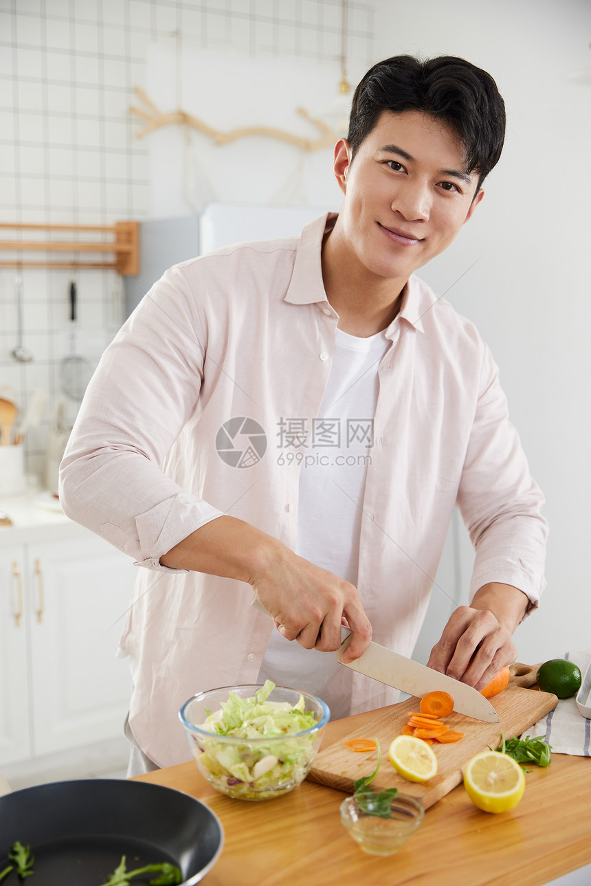帅气的年轻男士在厨房切菜图片