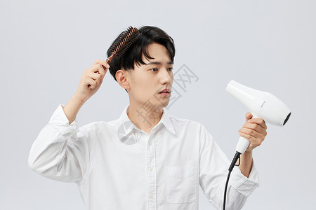 青年男性使用吹风机打理头发图片