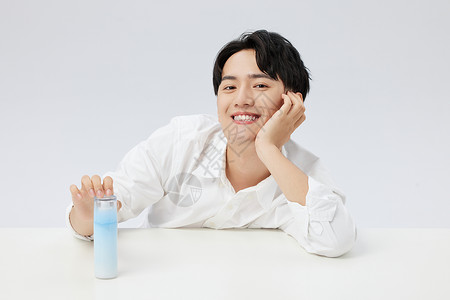 韩系男性手拿精华乳液瓶图片
