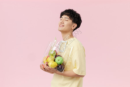 拿苹果的男生韩系帅哥手抱水果袋侧面背景