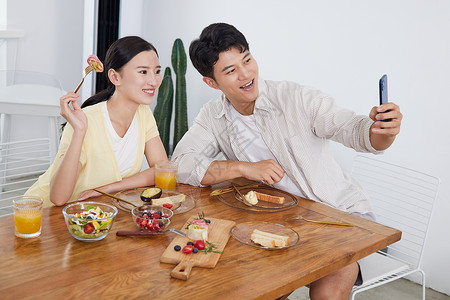 朋友圈年轻情侣在餐厅用智能手机自拍背景