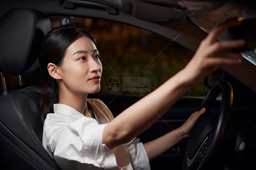 白领女性司机夜间驾车检查后视镜图片