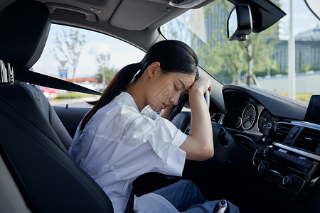 女性司机头靠方向盘休息背景图片