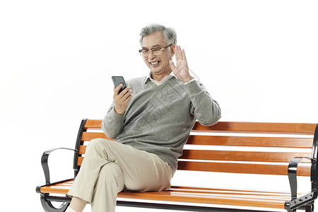 老年人坐在长椅上手机视频通话打招呼背景图片