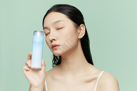 补水保湿养颜女性手拿乳液瓶展示背景