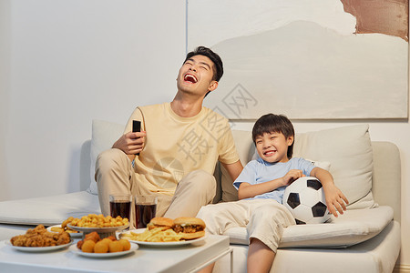 沙发上的食物和饮料爸爸和儿子坐沙发上看世界杯背景