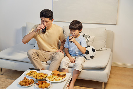 沙发上的食物和饮料父子坐沙发上看球赛背景