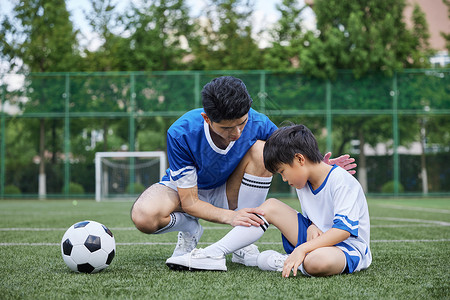 踢球训练父亲给男孩检查受伤的膝盖背景