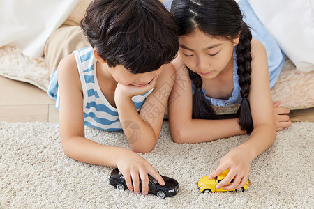 姐弟俩趴在地毯上玩汽车模型背景