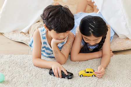 儿童小汽车两个小朋友趴在地毯上玩汽车模型背景