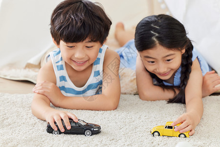 姐弟俩趴在地毯上玩汽车模型背景