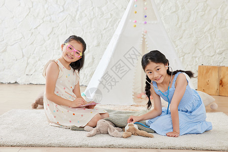 玩偶布娃娃两个小女孩在扮医生过家家背景