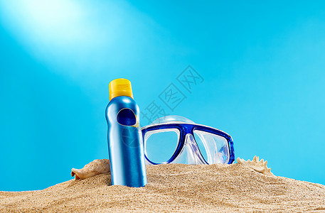 夏日沙滩上的防晒霜和防护镜背景图片