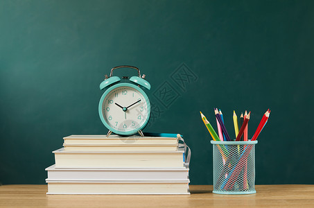 教师桌面堆叠在桌上的书本和闹钟背景
