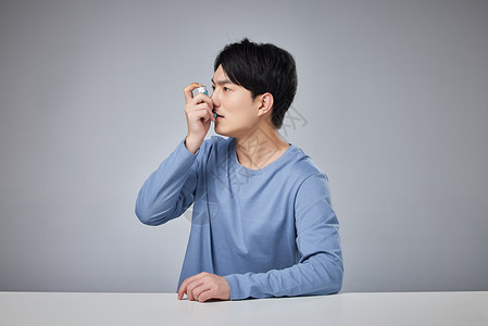 男性病患手拿哮喘吸入器年轻男性使用哮喘吸入器背景