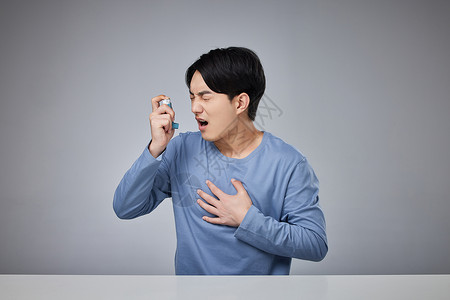 男性病患手拿哮喘吸入器年轻男性使用哮喘吸入器背景