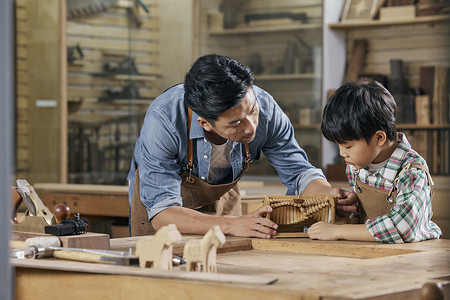 业余工作男木匠师傅和小男孩讲解手工音乐盒制作背景