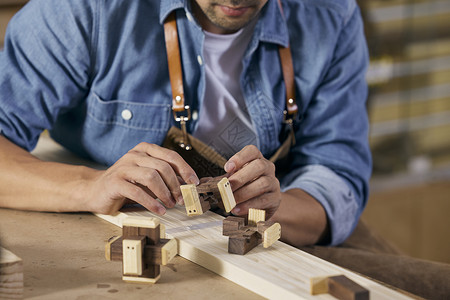 工人专注男木匠把玩木质鲁班锁背景