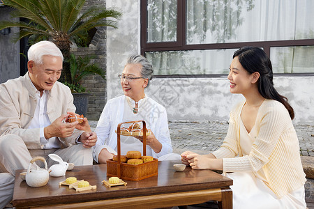 中秋节家人团聚庭院里吃月饼图片