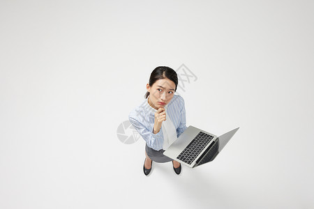 创意俯拍职业商务女性拿笔记本电脑思考图片