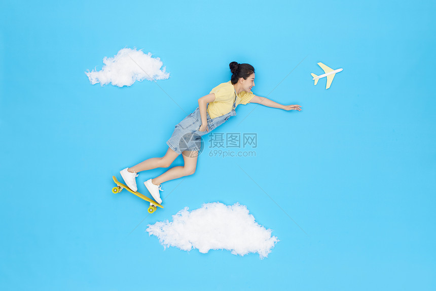 创意俯拍美女云朵上踩滑板飞行旅行图片
