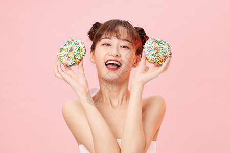 拿甜甜圈扮可爱的年轻女性高清图片