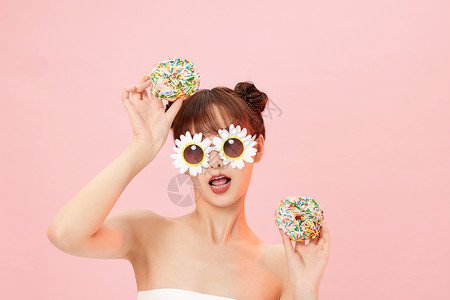 拿甜甜圈扮可爱的年轻女性图片