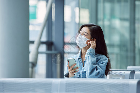 机场候机厅戴口罩的女性看手机高清图片