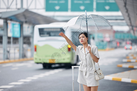 撑着伞在路边焦急打车的商务女性图片