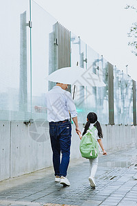 雨天 儿童年轻父亲牵手接女儿放学背景