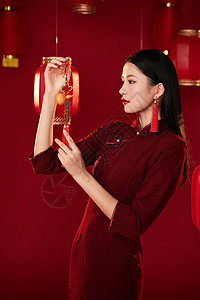 穿旗袍的年轻女子端详中国结装饰图片