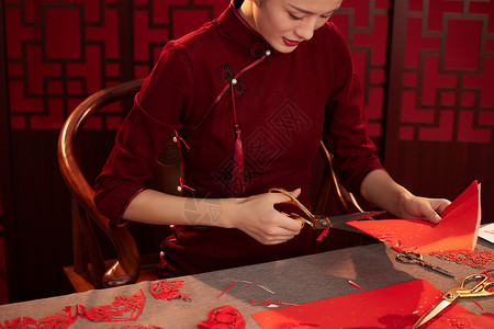 红色中式装饰正在剪窗花的旗袍美女背景
