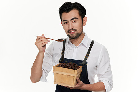 男性咖啡师拿着一勺咖啡豆面带微笑背景图片