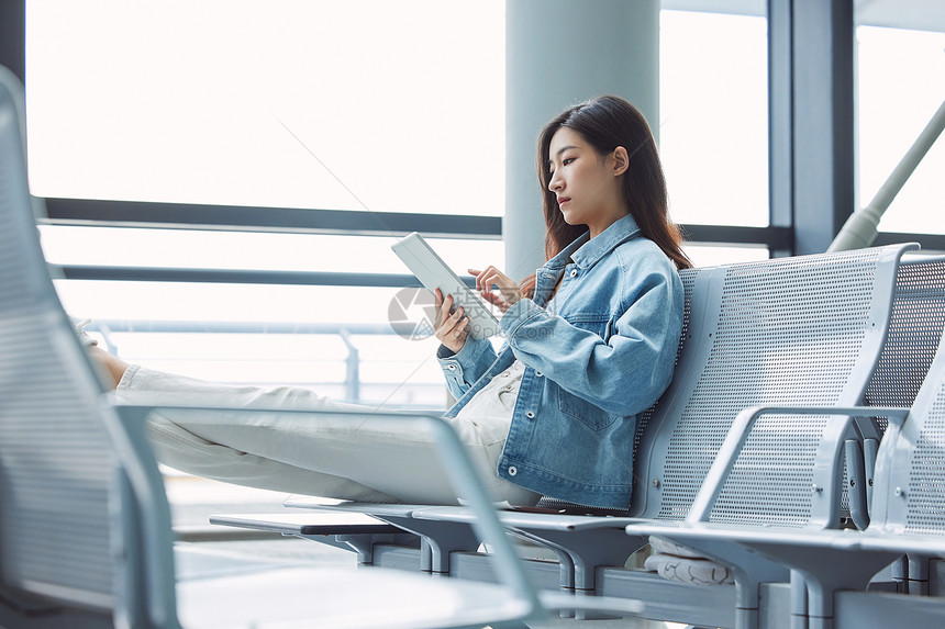 女性在机场椅子上休息使用平板电脑图片
