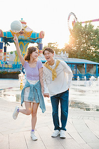 爱在七夕海报拿着棉花糖的年轻情侣在游乐园里约会背景