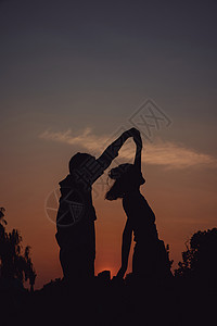 夕阳下舞蹈的情侣剪影图片
