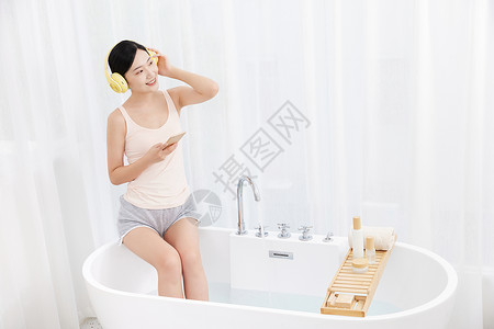 年轻女性坐在浴缸前听音乐图片